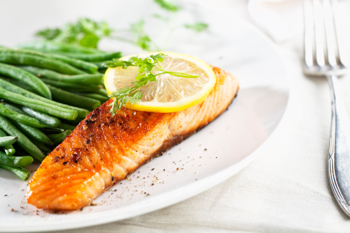 salmon and green beans on a plate, with a slice of lemon and some chervil