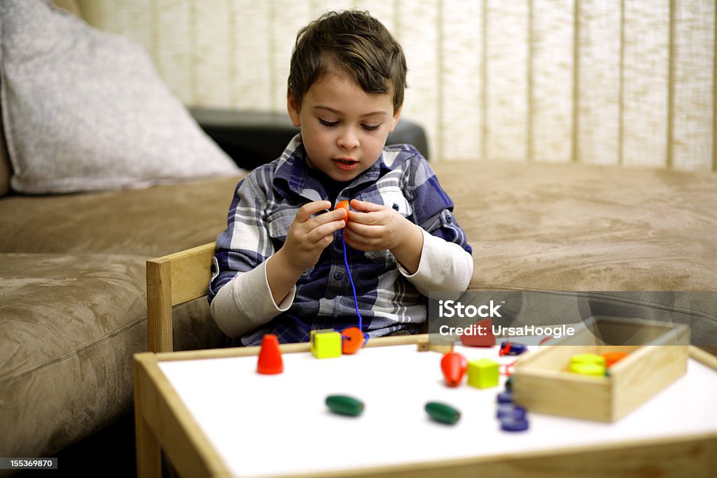 Lacing beads Boy with autism stringing together large beads that are easy to grasp. This activity promotes hand-eye coordination and offers opportunity for increased attention to task.  Child Stock Photo