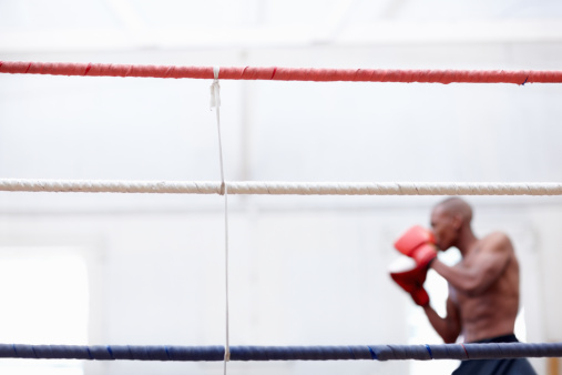 African-American boxer practicing in the ring - copyspace