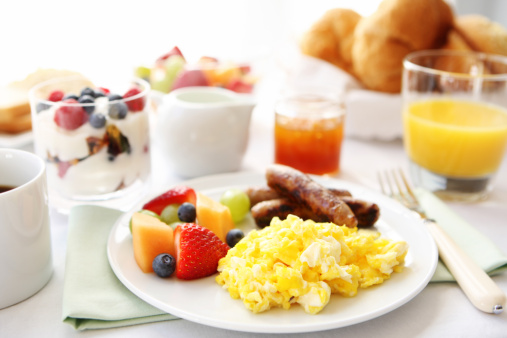 Breakfast table with eggs, fruit, and sausages