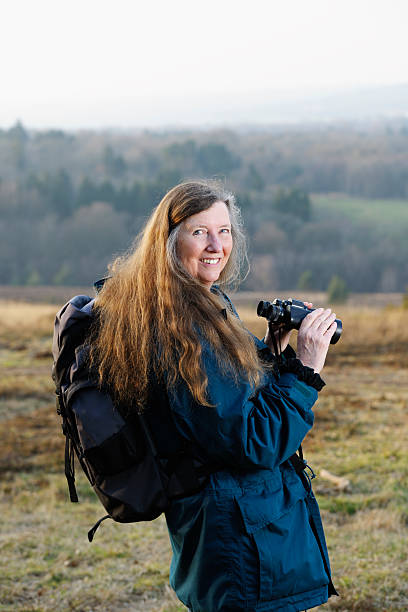 Active Senior / Mature Woman Holding Binoculars Active senior/ mature woman holding binoculars while out hiking. ashdown forest photos stock pictures, royalty-free photos & images