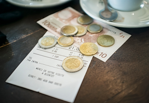 A bill with payment in Euros on the table of a cafe.