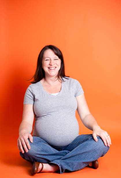 istock Pregnant Women Laughing While On Orange Background 155370660