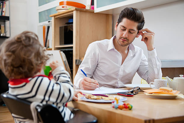 istock Father and son at breakfast table as father finishes work 155372030