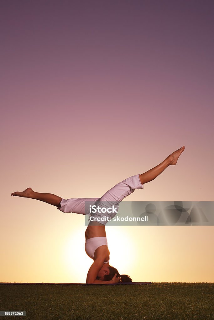 Fare la verticale sulla testa di Yoga al tramonto - Foto stock royalty-free di Adulto