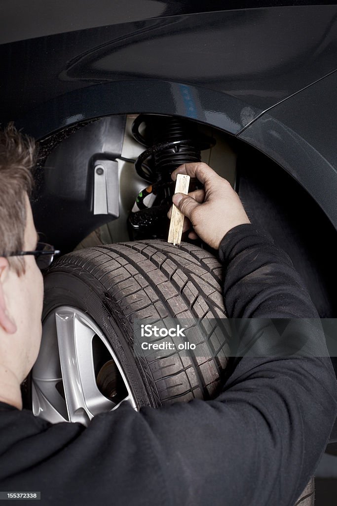Mecânico está verificando a derrapar profundidade de pneu - Foto de stock de Amortecedor royalty-free