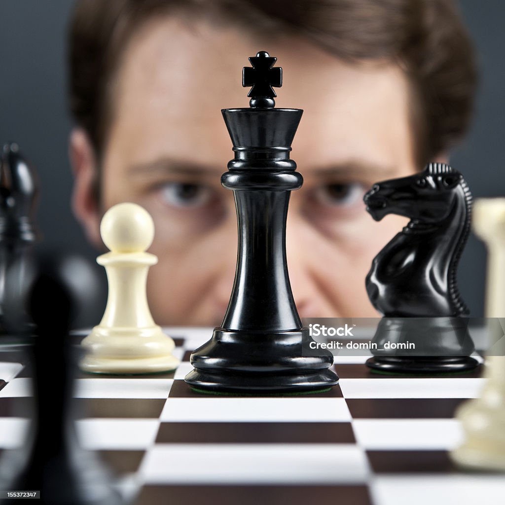 Selective focus, man's eyes on chess pieces Chess player or businessman thinking on next move. Chess board, square composition. Chess Stock Photo