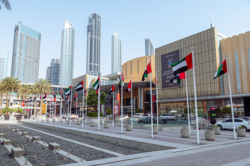 Dubai, United Arab Emirates - June 21, 2023: Entrance of the Dubai Mall with waving flags of United Arab Emirates on a flagpole