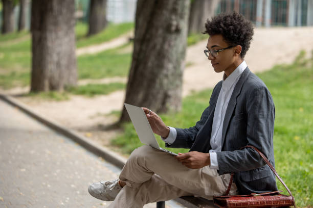 istock Curly-haired young digital nomad working in the park 1553725201