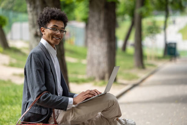istock Curly-haired young digital nomad working in the park 1553725475