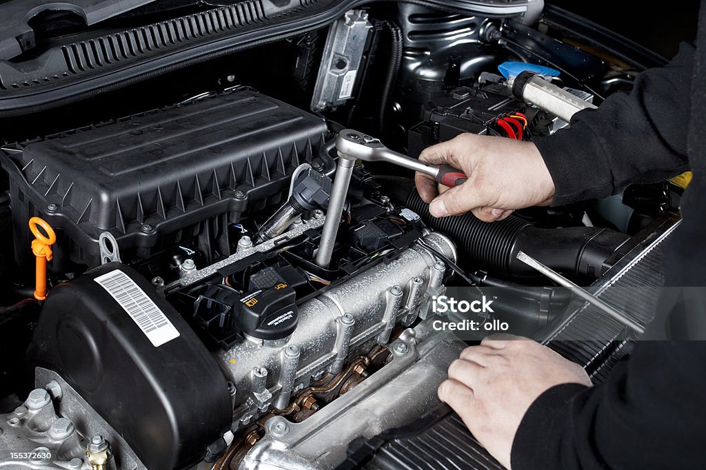 Mécanicien est unscrewing le démarrage d'une voiture moderne chevilles - Photo de Bougie d'allumage libre de droits