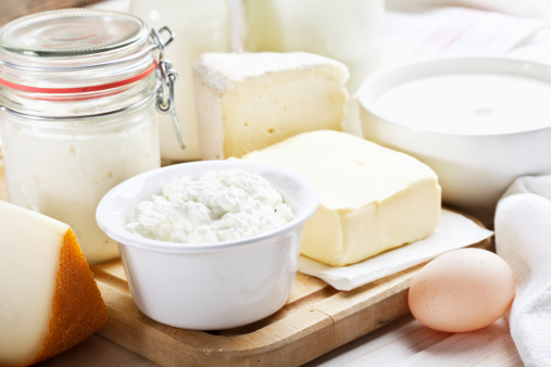 dairy products such as cheese, yoghurt, butter, cottage cheese, milk in a glass bottle and a egg on wooden table