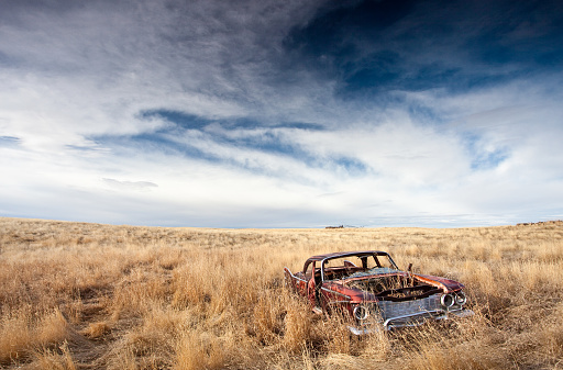 An abandoned car on the plains. Alberta, Canada. Rural scenic. HDR colour image. A rusty automobile sits abandoned in a ragged field of fescue on the great plains. Old rusty cars can make for great subjects for photography! Image taken with Canon Mark II body and l series lens. 