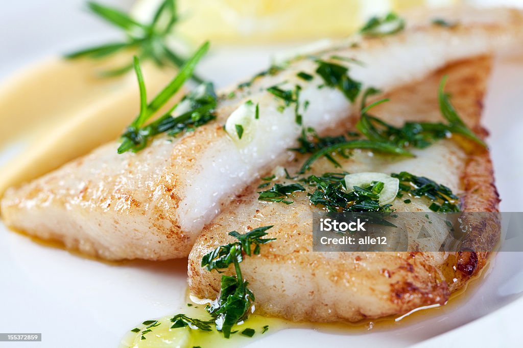 Closeup photograph of white fish Fillet of white fish with parsley, garlic, olive oil and lemon sauce. Fish Stock Photo