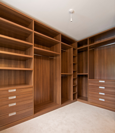 a walk-in wardrobe in a luxury new home ready to fill. Beautifully constructed from walnut with ample shelves, hanging bars and storage space in general. 