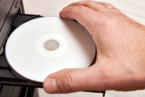 istock A man inserts a disc into a disc player on his computer. Technologies of information carriers of CD, DVD, BD format. 1553732402