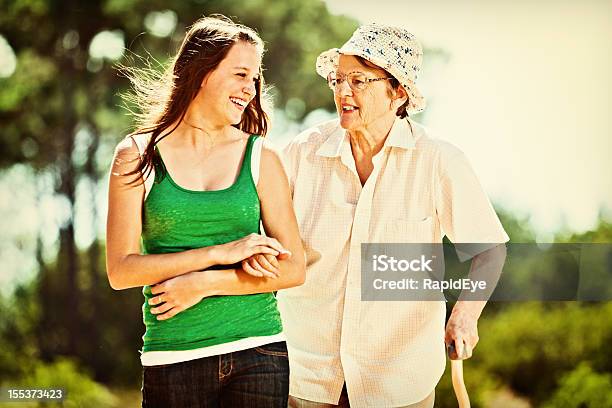 Granddaughter And Grandmother Smile As They Go Walking Together Stock Photo - Download Image Now