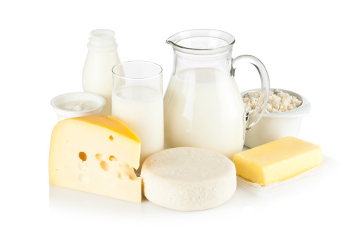 Image of dairy products shot on reflective white backdrop. Includes: milk, various types of cheese, butter, ricotta, milk cream and yogurt. A milk pitcher and a glass of milk are in the center while the rest of the products are around them. A soft shadow is visible in the foreground. The predominant color is white. DSRL studio shot with Canon EOS 5D Mk II  
