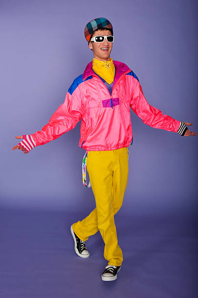 Teenager in 1980s fluorescent pink and yellow with cap A teenage boy with braces on his teeth dressed in 1980's styled clothing and dancing nerd teenager stock pictures, royalty-free photos & images