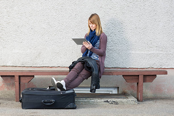 istock Young woman sitting on train station,working with digital tablet 155373621