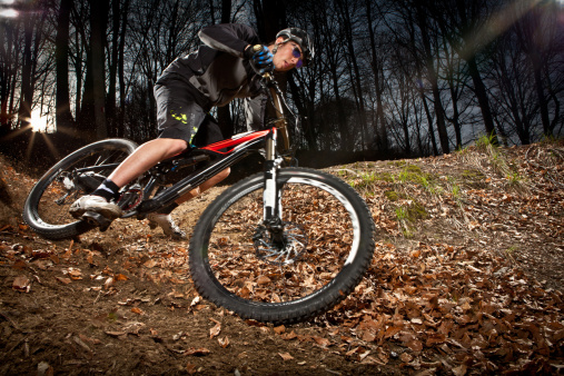 Downhill enduro mountain bike curve in the woods. Motion blur, real flash flare effect.