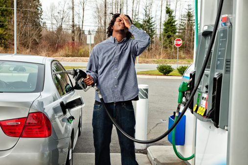 Photo of a young man agonizing over how much it costs to fill his gas tank.