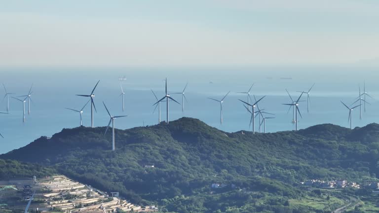 A bird's eye view of a wind farm on a hilltop by the sea