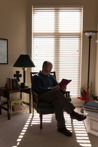 istock Senior Reads Bible Sunday Morning With Cross Shape Window Shadow 155374045