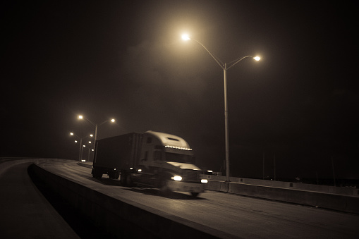 semi-truck with container on flatbed on the city at night leaving the port of miami