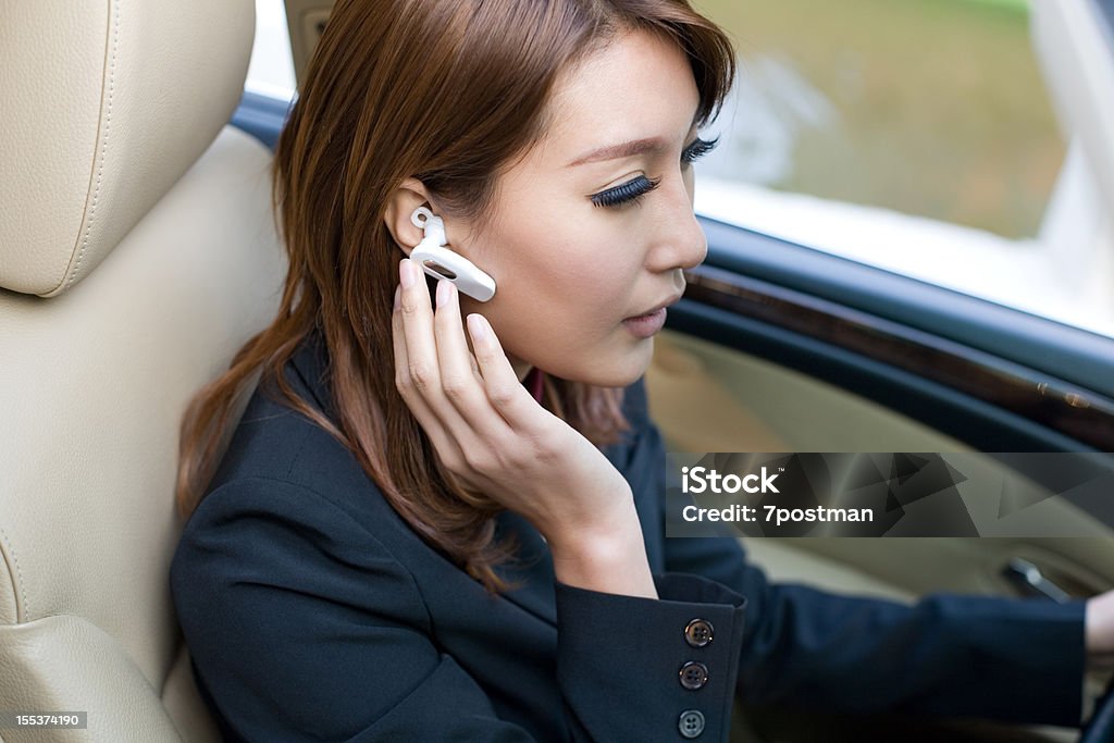 Bellissima giovane donna guida auto parlando su cuffie Bluetooth - Foto stock royalty-free di Abbigliamento casual