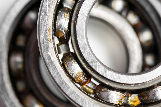 Close-up of silver-colored ball bearing over white backdrop Closeup of a pair of bearing used in motor for home appliances. Top view on a white background. ball bearing photos stock pictures, royalty-free photos & images