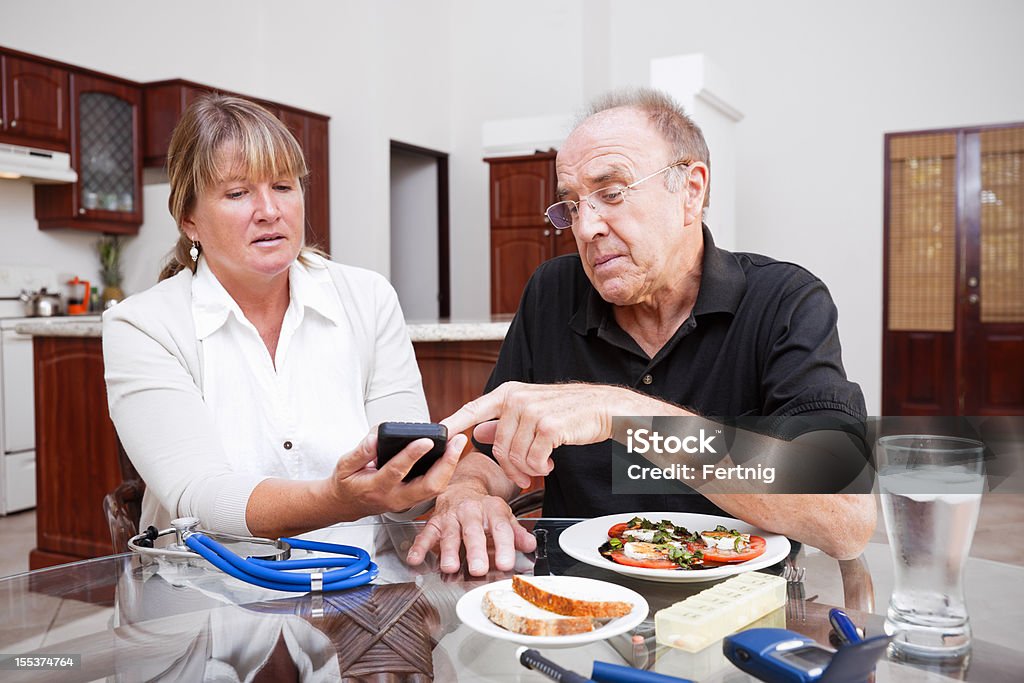 Health care professional and senior diabetic patient A photograph  of a health care professional showing a senior patient with diabetes how to access his blood sugar readings on a hand held device or smartphone. Diabetes Stock Photo