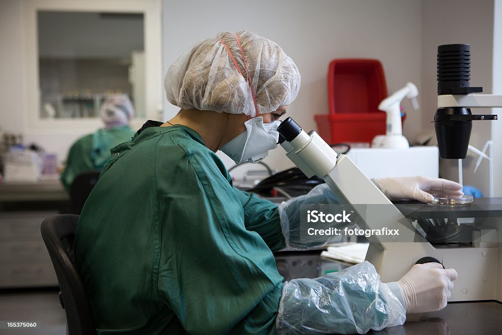 Investigación médica: Los científicos es a través de un microscopio en sus muestras - Foto de stock de ADN libre de derechos