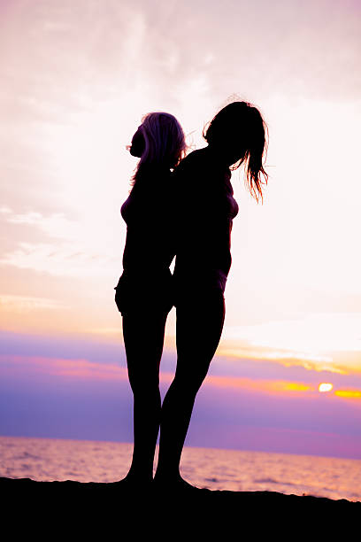 istock Two young woman standing at sunset beach 155375129