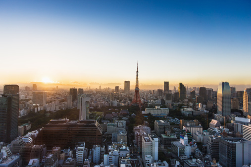 Aerial panorama of Downtown Tokyo at afternoon, with view of high-rise towers clustering in Shibuya area and an arterial highway stretching among crowded buildings out to distant horizon in hazy dusk