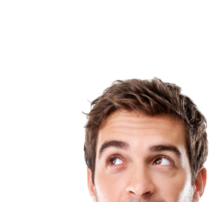 Serious caucasian guy wearing classic blue shirt holding hand on chin and looking at camera isolated on grey background. Real studio shot.