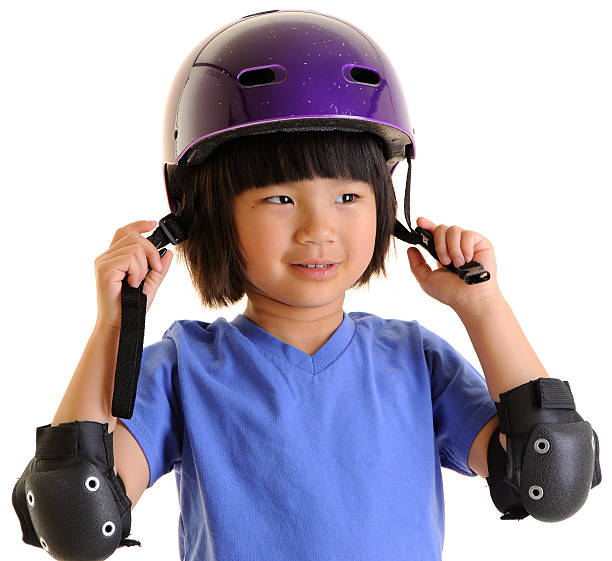 Little Girl Putting on Helmet and Elbow Pads stock photo
