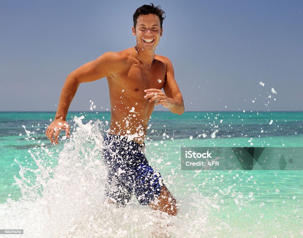 Atractivo hombre corriendo en la playa (XXXL - Foto de stock de 20-24 años libre de derechos