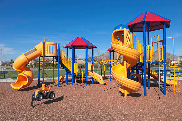 Colorful kids outdoor playground equipment with slides Colorful Playground In A Park During Early Summer schoolyard stock pictures, royalty-free photos & images