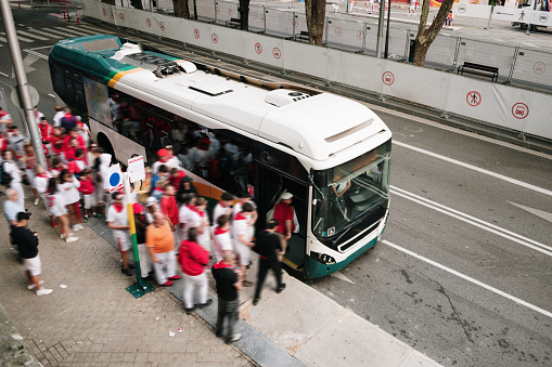 A crowd of people in motion entering a bus in a city