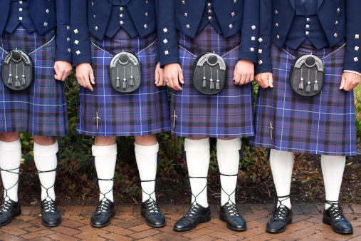 Four men dressed in formal Scottish kilts.