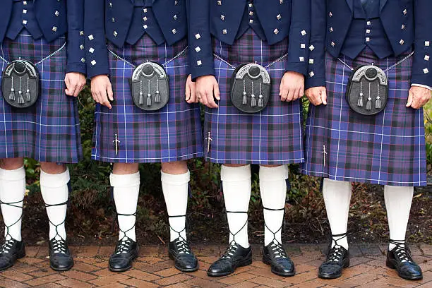 Four men dressed in formal Scottish kilts.