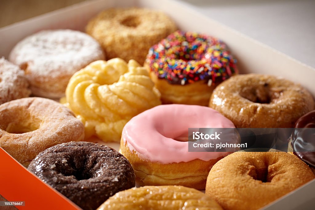 Doughnuts Tight shot of box containing a dozen doughnuts, shallow focus.  Professionally color corrected, exported 16 bit depth, retouched and saved for maximum image quality. Doughnut Stock Photo