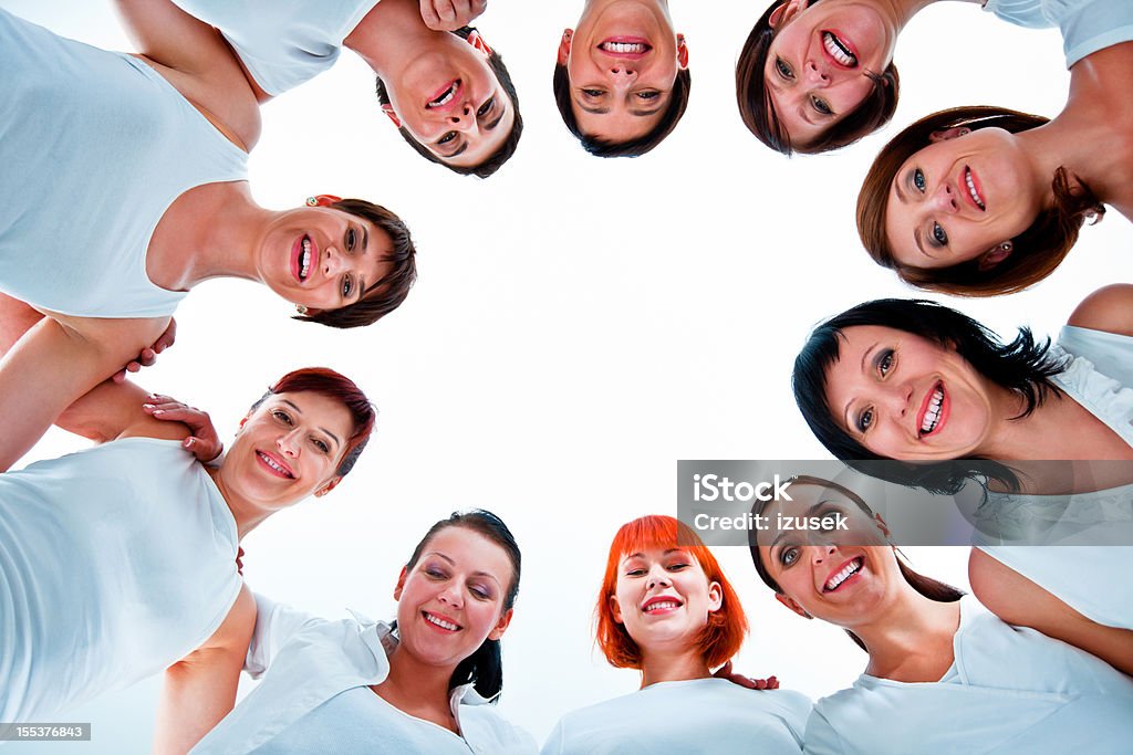 Togetherness Group of women standing in the circle, smiling at the camera against white background. Low angle view. Adult Stock Photo
