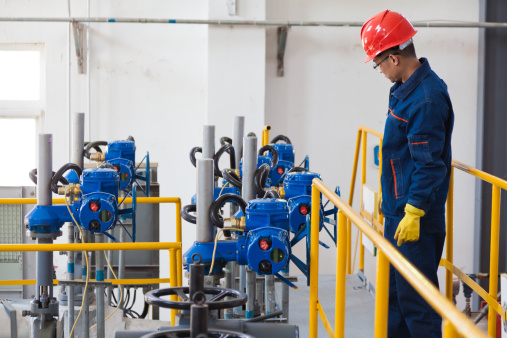 Engineer checking the oil pipeline equipment in crude oil storage workshop, Beijing, China.