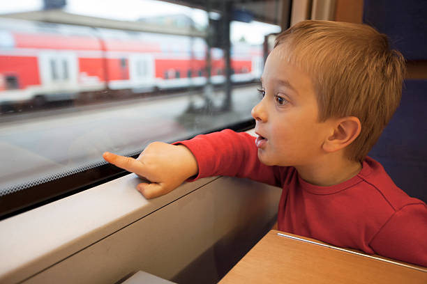 tre anni ragazzo in viaggio in treno in una finestra che indica - surprise child 4 5 years little boys foto e immagini stock