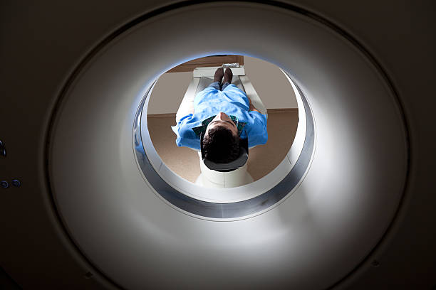 mann mit einer medizinischen untersuchung über magnetresonanztomographie - mri scanner stock-fotos und bilder