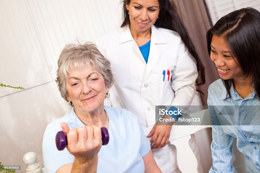 Donna anziana. Terapia fisica con un medico, membro della famiglia. Il sollevamento pesi. - Foto stock royalty-free di Gruppo di persone