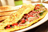 A folded egg omelets filled with chopped ham and vegetables