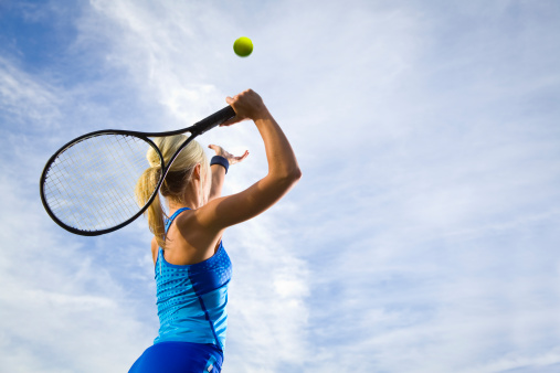 Woman on tennis court playing tennis. Serving ball.